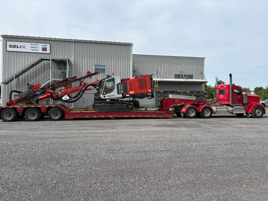 Camion VIAX rouge tirant une foreuse Sandvik sur fardier surbaissé